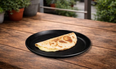 Crepe folded on black plate atop wooden table with potted plants in background
